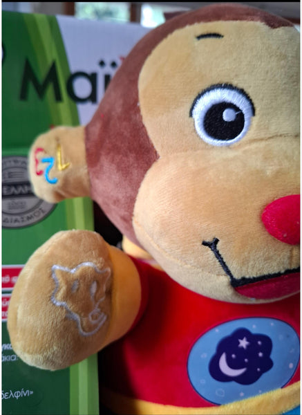 Plush monkey toy with a red shirt and blue star design, in package box with greek text